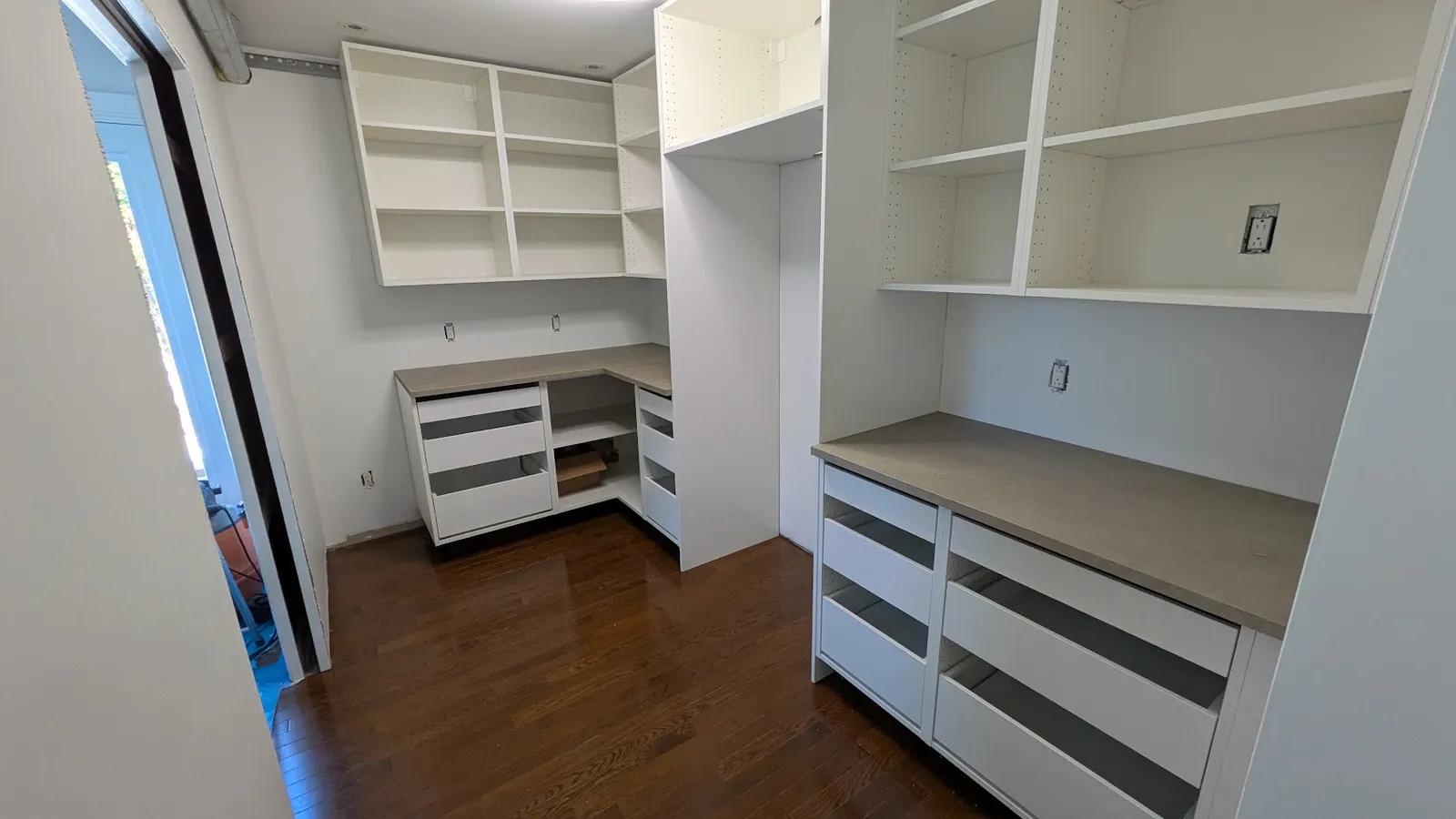 Corner of a walk-in pantry in Laval with deep drawers and shelving above the countertop