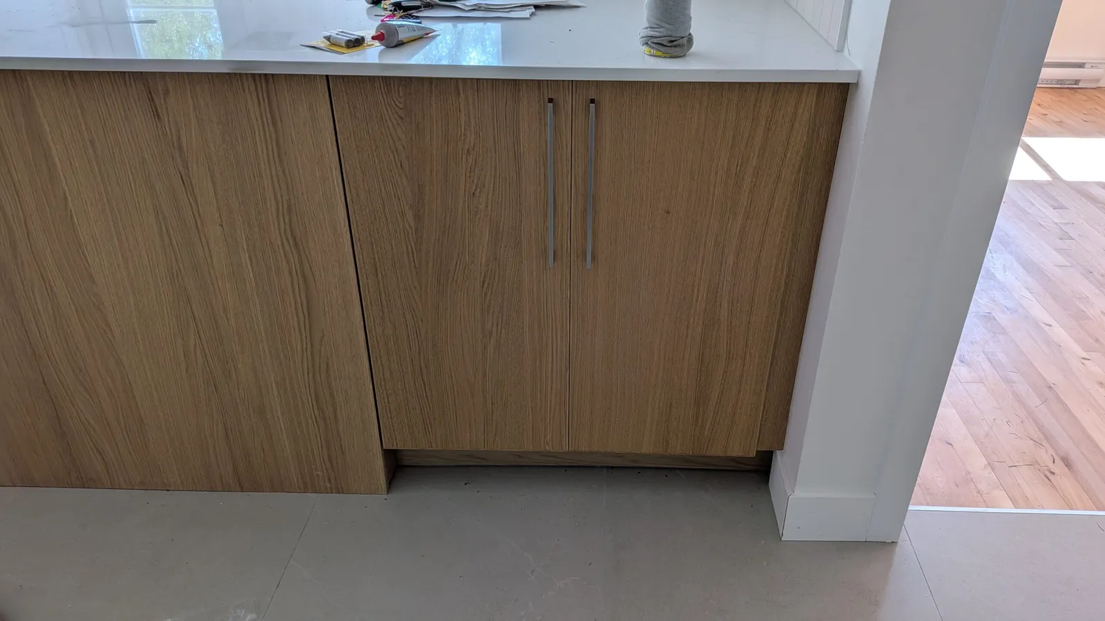 Natural oak-finish base cabinets with bar handles under a white countertop in a Brossard kitchen