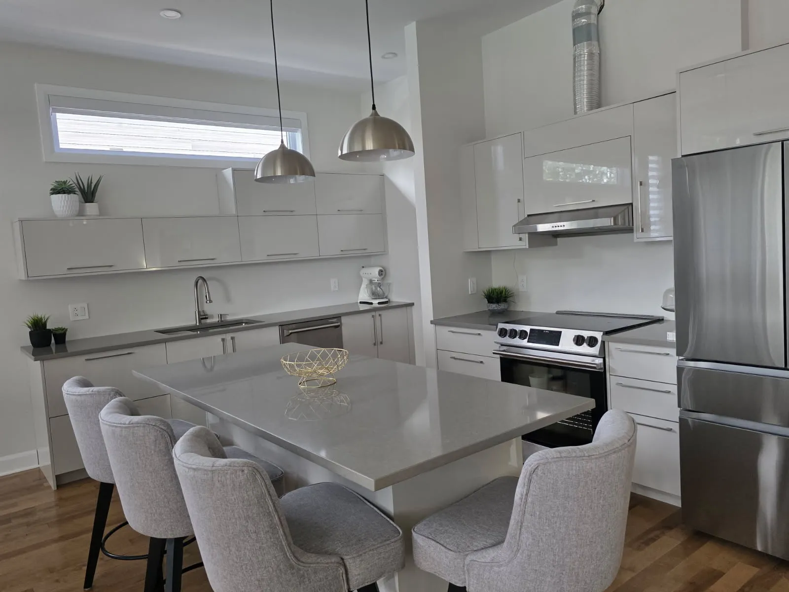 L-shaped RONA kitchen in Laval with island, stainless refrigerator and pendant lights