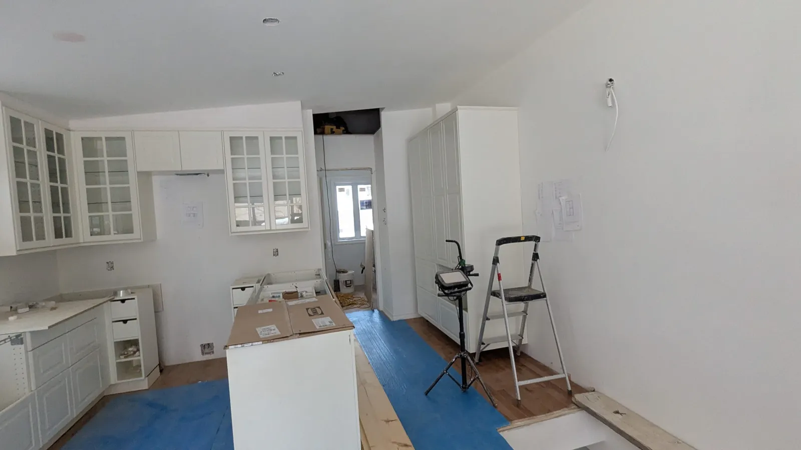 Glass-front upper cabinets and a tall pantry cabinet during a kitchen installation in Deux-Montagnes