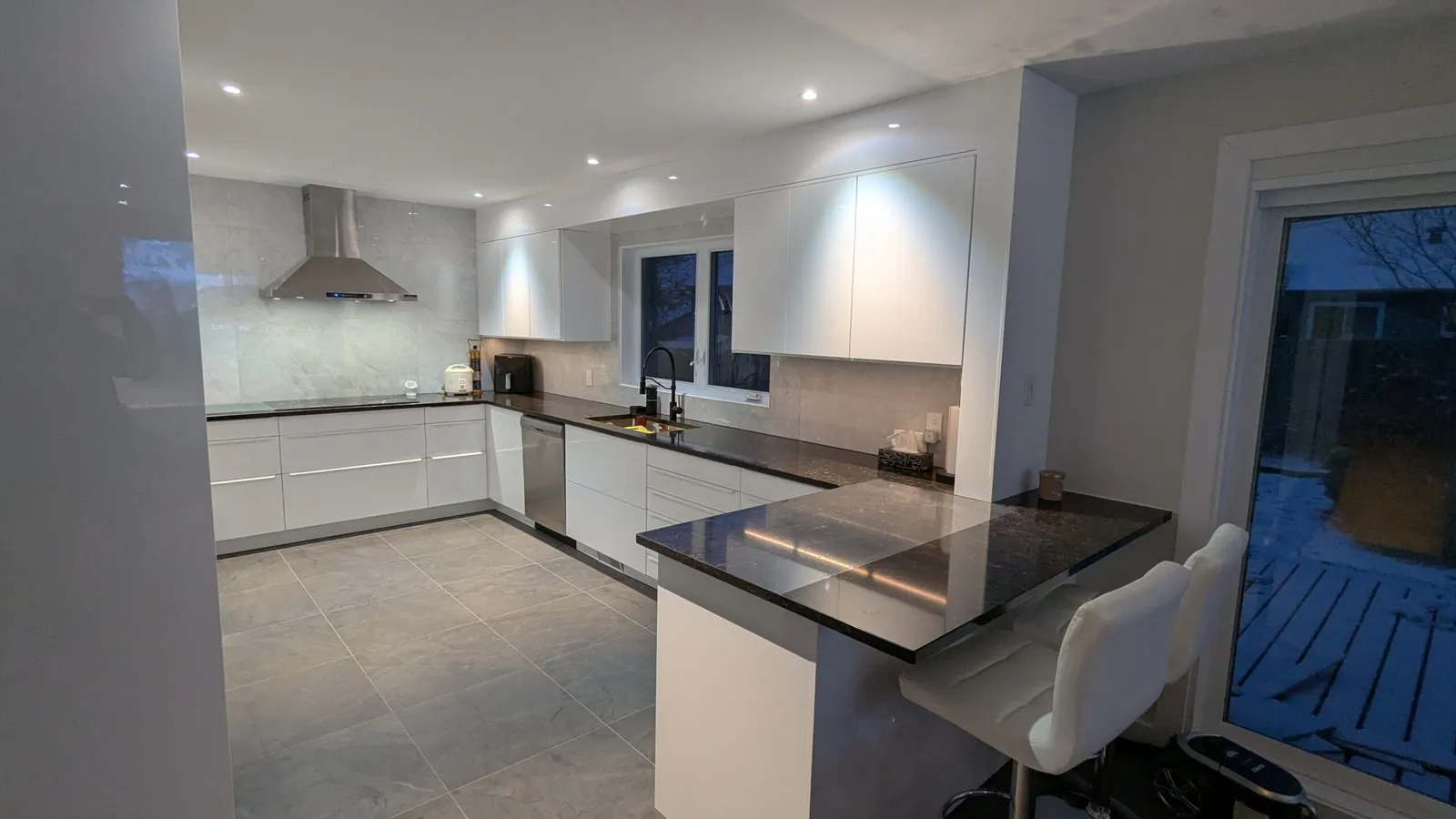 High-gloss white base and wall cabinets with a stainless range hood and patio door in a Kirkland kitchen