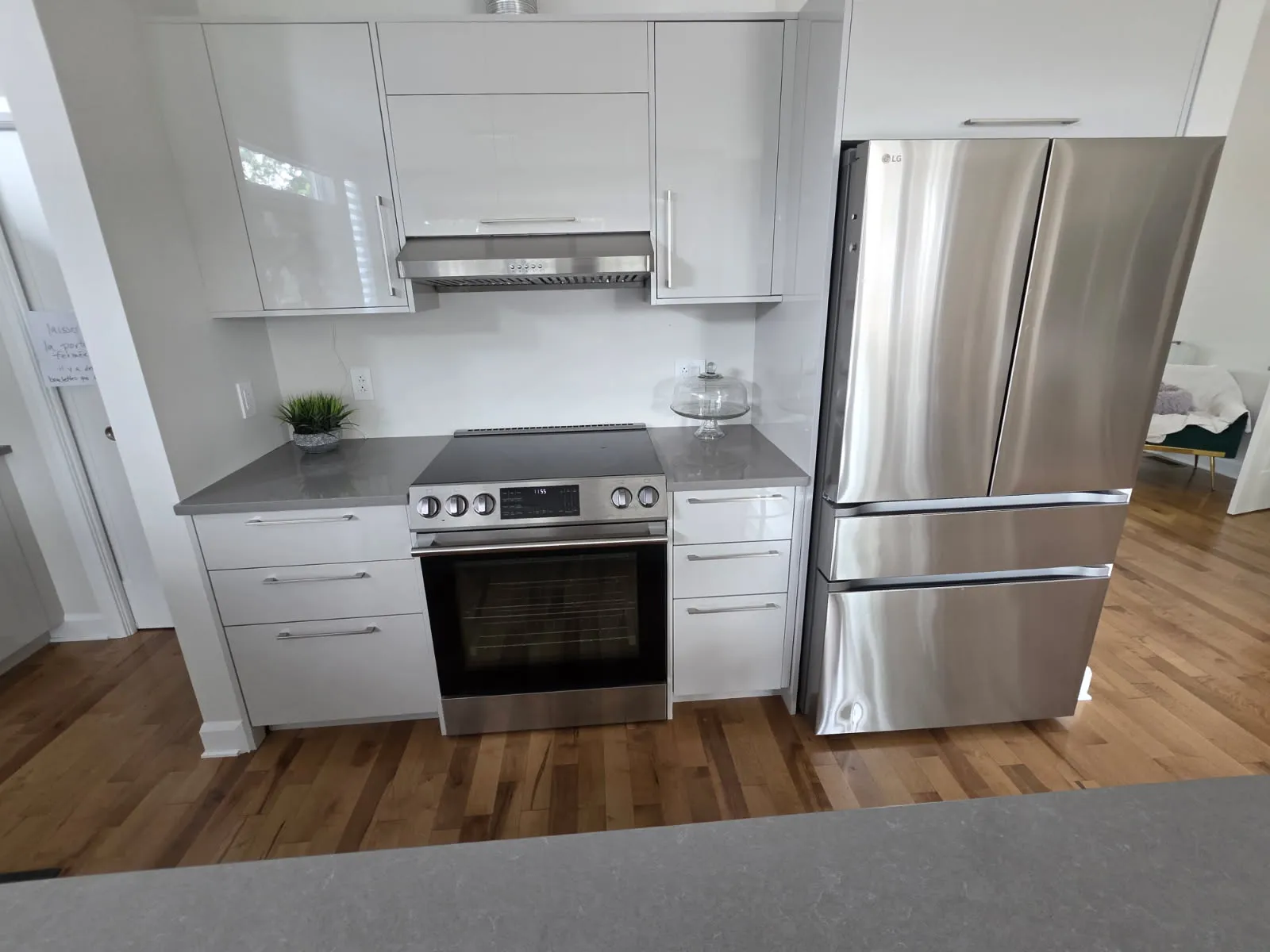 Stainless electric range, range hood and French-door refrigerator in a modern white kitchen in Laval